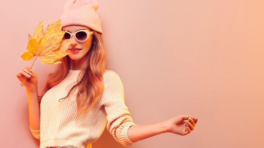 Woman in sunglasses holds fall leaves